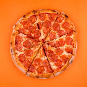 pizza-di-saloni-al-salame-piccante-e-cotta-intera-su-uno-sfondo-arancione-brillante-affettata-con-una-pasta-224834834